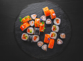 set of sushi roll with salmon, avocado, cream cheese, cucumber, rice, tuna in plate on black background