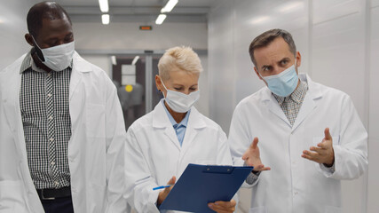 Team of physicians wearing lab coat and protective mask discussing patient medical test