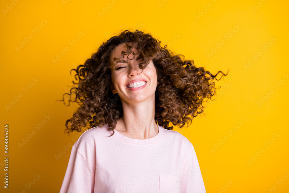 Wall mural Photo portrait of curly woman throwing hair isolated on vivid yellow colored background