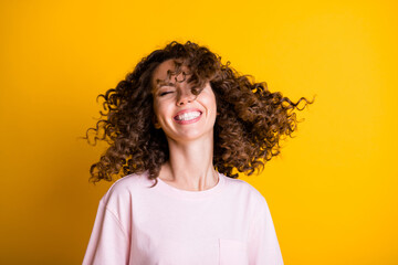 Photo portrait of curly woman throwing hair isolated on vivid yellow colored background