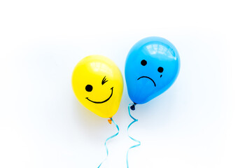 Emotions concept. Happiness and depression faces on balloons, top view