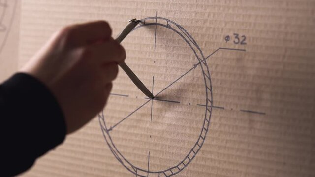 Man draws a circle with a compass on a drawing.