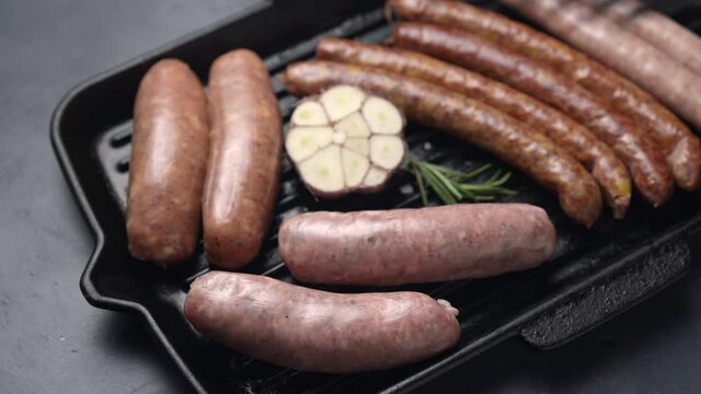 The cook puts the sausage on the grill with tongs. The frame moves along the camera