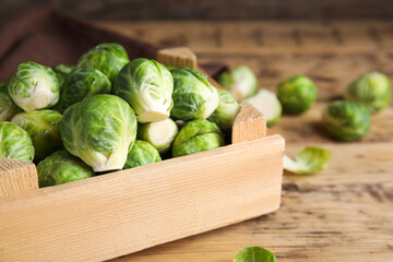 Crate with fresh Brussels sprouts on wooden table, closeup