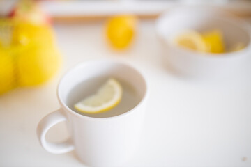 Fototapeta na wymiar Cup of lemon tea on a white table surrounded by lemons