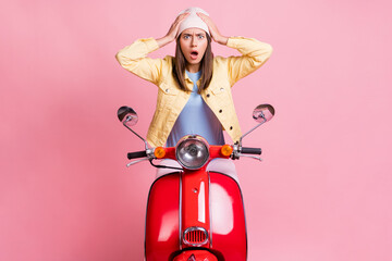 Fototapeta na wymiar Photo of young shocked hear bad news attractive woman girl female hold hands head ride red motorbike isolated on pink color background