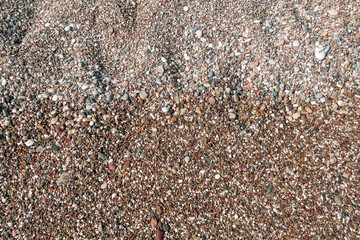 Wet and dry small sea stones pebbles on the beach after the wave as background
