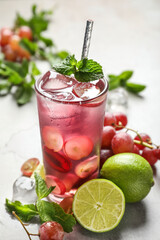 Soda water with grapes, ice, lime and mint on table. Refreshing drink