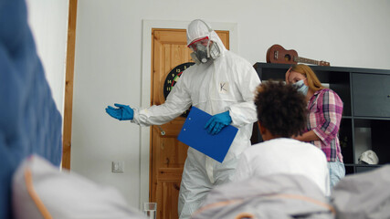 Doctor in protective overall taking sick african child in hospital for test