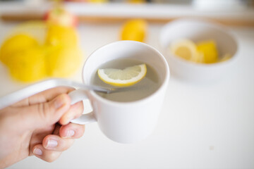 Hand holding a cup of lemon tea with a straw and lemon slice