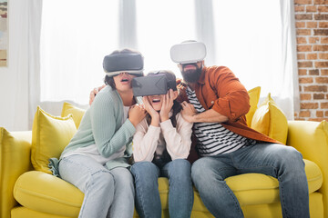 scared hispanic family using vr headsets while sitting on sofa at home