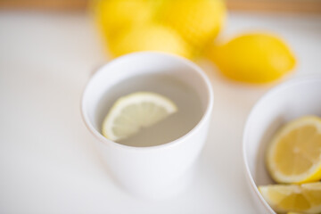 Cup of lemon tea on a white table surrounded by lemons