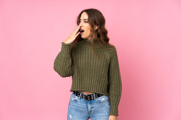 Young woman over isolated pink background yawning and covering wide open mouth with hand