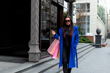 hot Sale. Beautiful young fashion woman with shopping bags near shop window calling smart phone, toned. shopping woman fun phone