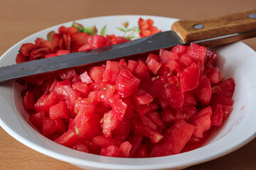 Cutted chopped Tomatoes in retro glass bowl on an old wooden table as detailed close-up shot (selective focus)