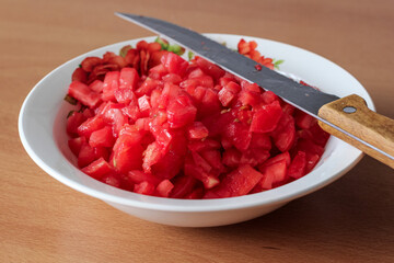 Cutted chopped Tomatoes in retro glass bowl on an old wooden table as detailed close-up shot (selective focus)