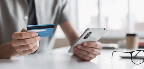 Man holding credit card and using smartphone at office panoramic banner, businessman shopping online, e-commerce, internet banking, spending money, working from home concept