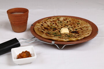 Hot Aloo Paratha on Tawa with butter, tea, and pickle.