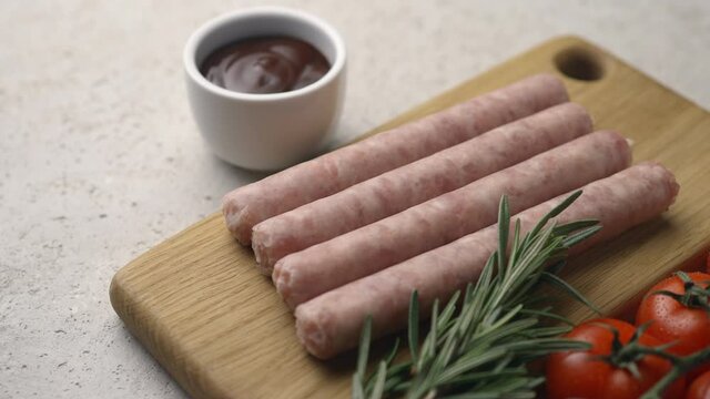 Grilled sausages on a wooden board with tomatoes, rosemary and tomato sauce, the camera moves forward, close-up