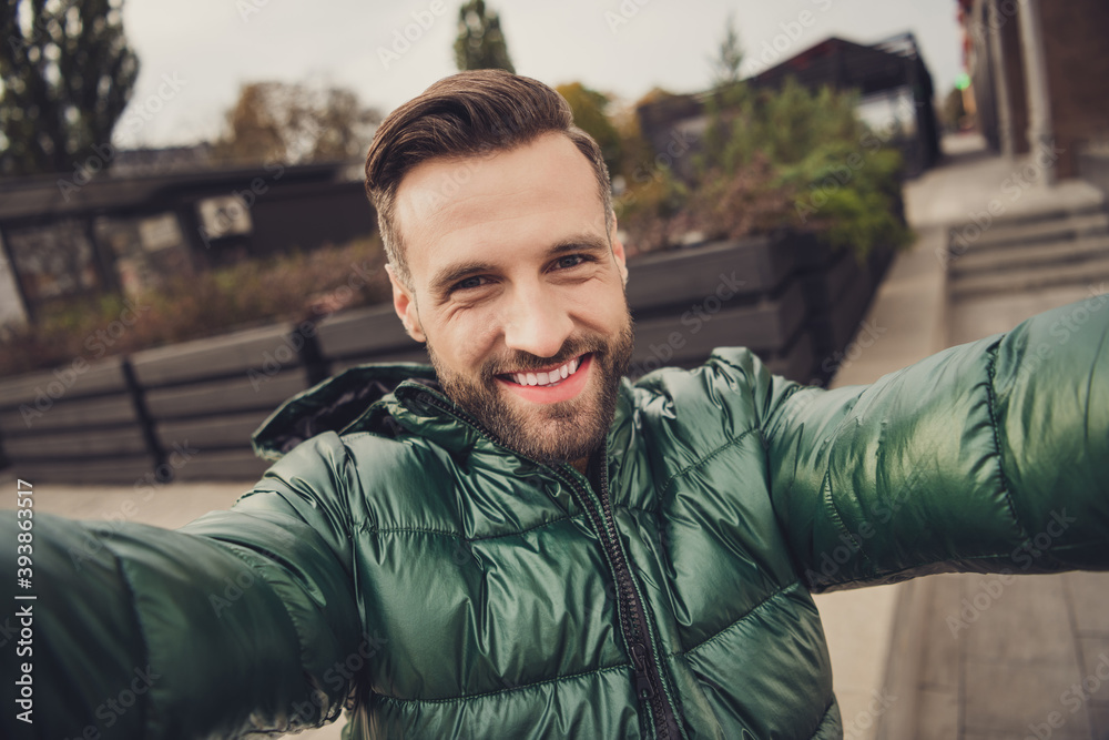 Sticker Photo of charming handsome young man wear green windbreaker making self video outside city street