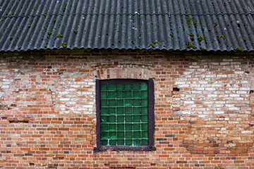 old brick wall with a window in the center and a slate roof, a historical building of the 17th century