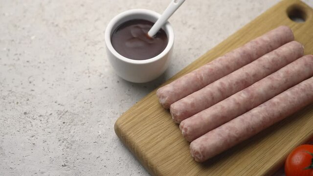 Grilled sausages on a wooden board with tomatoes and tomato sauce, frame moves to the side, close-up