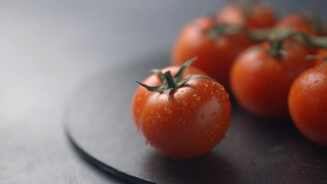 Farm tomatoes on a dark plate and dark background become harsh. Close-up
