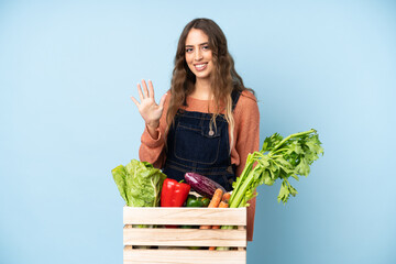 Farmer with freshly picked vegetables in a box counting five with fingers