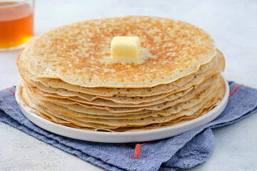 Crepes, thin pancakes with honey and butter on a white plate. Close up.