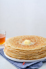 Crepes, thin pancakes with honey and butter on a white plate. Close up.