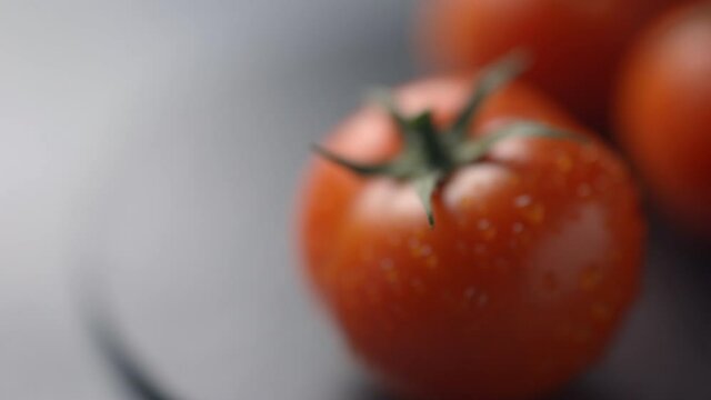 Farm tomatoes on a dark plate and dark background become harsh. Close-up