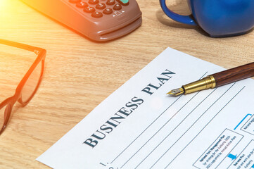 Business plan form on office desk with elegant pen and payment terminal. Business idea