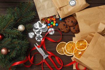 Flat lay composition with gift bags, treats and Christmas decor on wooden table. Creating advent calendar
