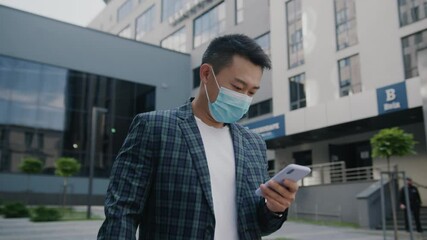 Asian young entrepreneur with face mask browsing internet on smartphone application walking the street looking around city center. Businessman. Mobile phone. Coronavirus. - Powered by Adobe