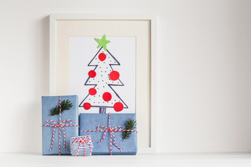 Christmas tree drawing in white frame and gifts.