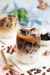 A glass of iced milk latte with fresh homemade Japanese coffee jelly with its bean in background....
