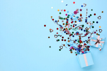 Colorful confetti and box on light blue background, top view. Space for text