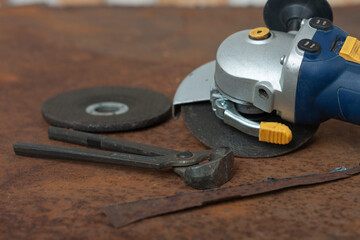 Black splitting pliers and angle grinder with thinner cut-off disc and  grinding disc on old rusty metal sheet