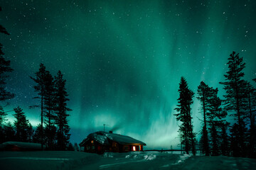 Northern lights Aurora Borealis activity over wooden cottage in winter Finland