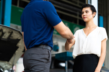 Expertise mechanic shaking hands with satisfied customer and working in automobile repair maintenance station garage. Satisfaction in service