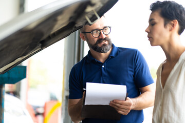 Mechanic man and woman customer check the car condition before delivery. automobile repair maintenance station garage.