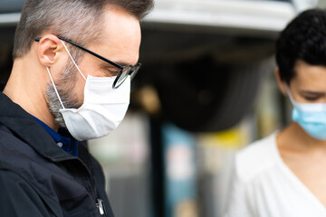 Mechanic man and woman customer wearing medical face mask protection coronavirus and check the car condition before delivery.