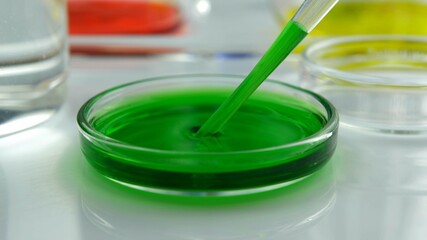 Green Liquid Dripping by Pipette into Glass Petri Dish in Laboratory