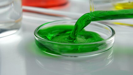 Pouring Green Liquid From Test Tube into Glass Petri Dish in Laboratory