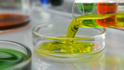 Pouring Yellow Liquid From Test Tube into Glass Petri Dish in Laboratory