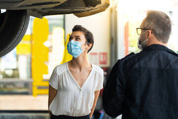 Mechanic man and woman customer wearing medical face mask protection coronavirus and check the car condition before delivery.