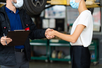 Mechanic man and woman customer wearing medical face mask protection coronavirus and check the car condition before delivery.