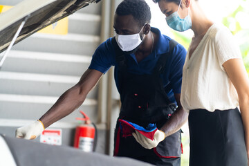 Mechanic man and woman customer wearing medical face mask protection coronavirus and check the car condition before delivery.