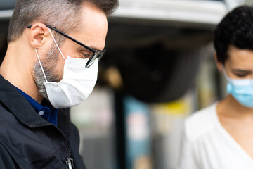 Mechanic man and woman customer wearing medical face mask protection coronavirus and check the car condition before delivery.