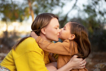 Mother and child walking and kissing in autumn park.